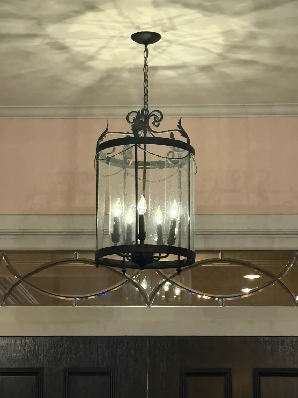 Decorative glass lantern chandelier casting ceiling shadows from indoor lighting