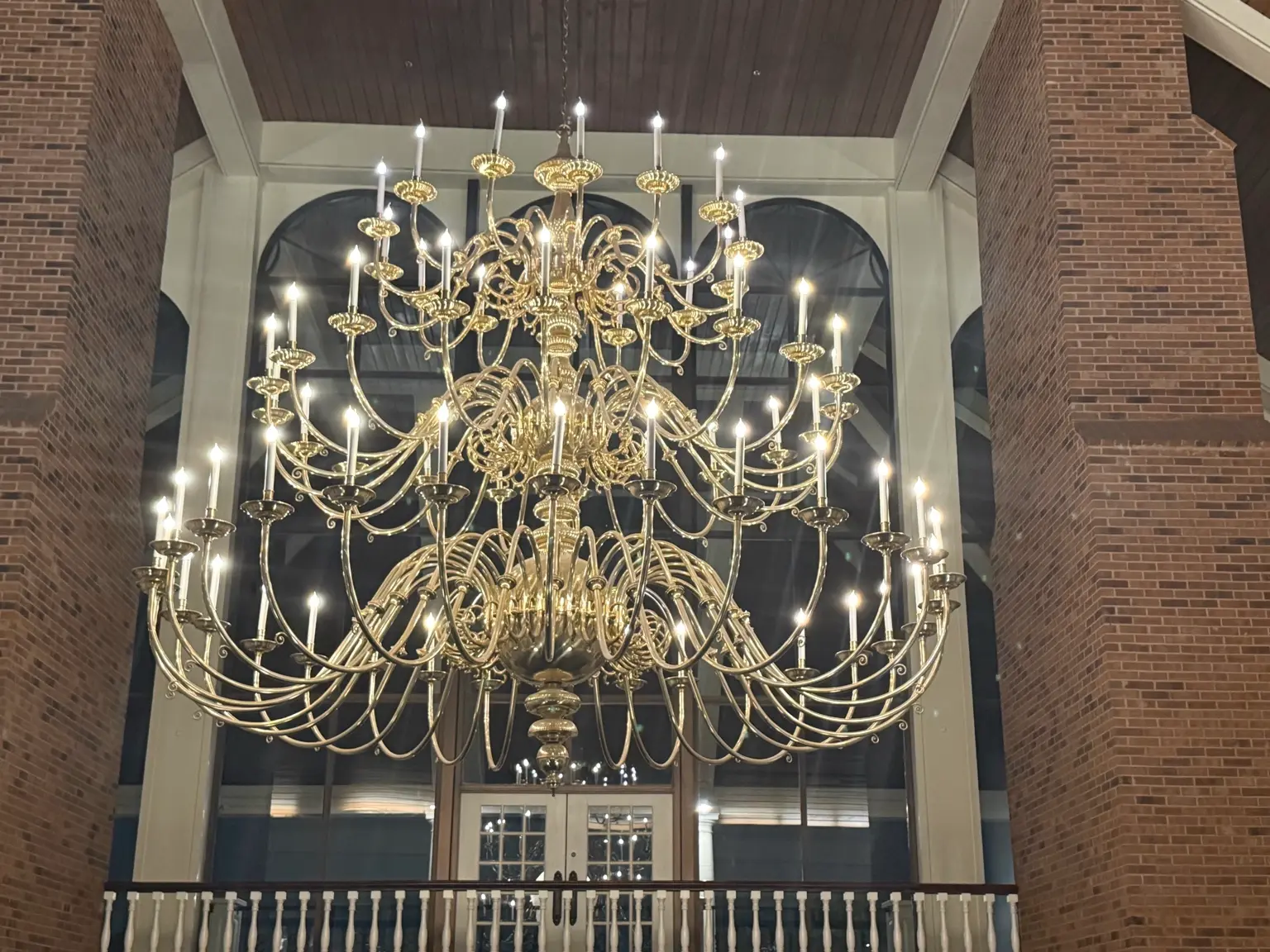 Large brass chandelier in a tall foyer showing multi bulb lighting scale and glare considerations