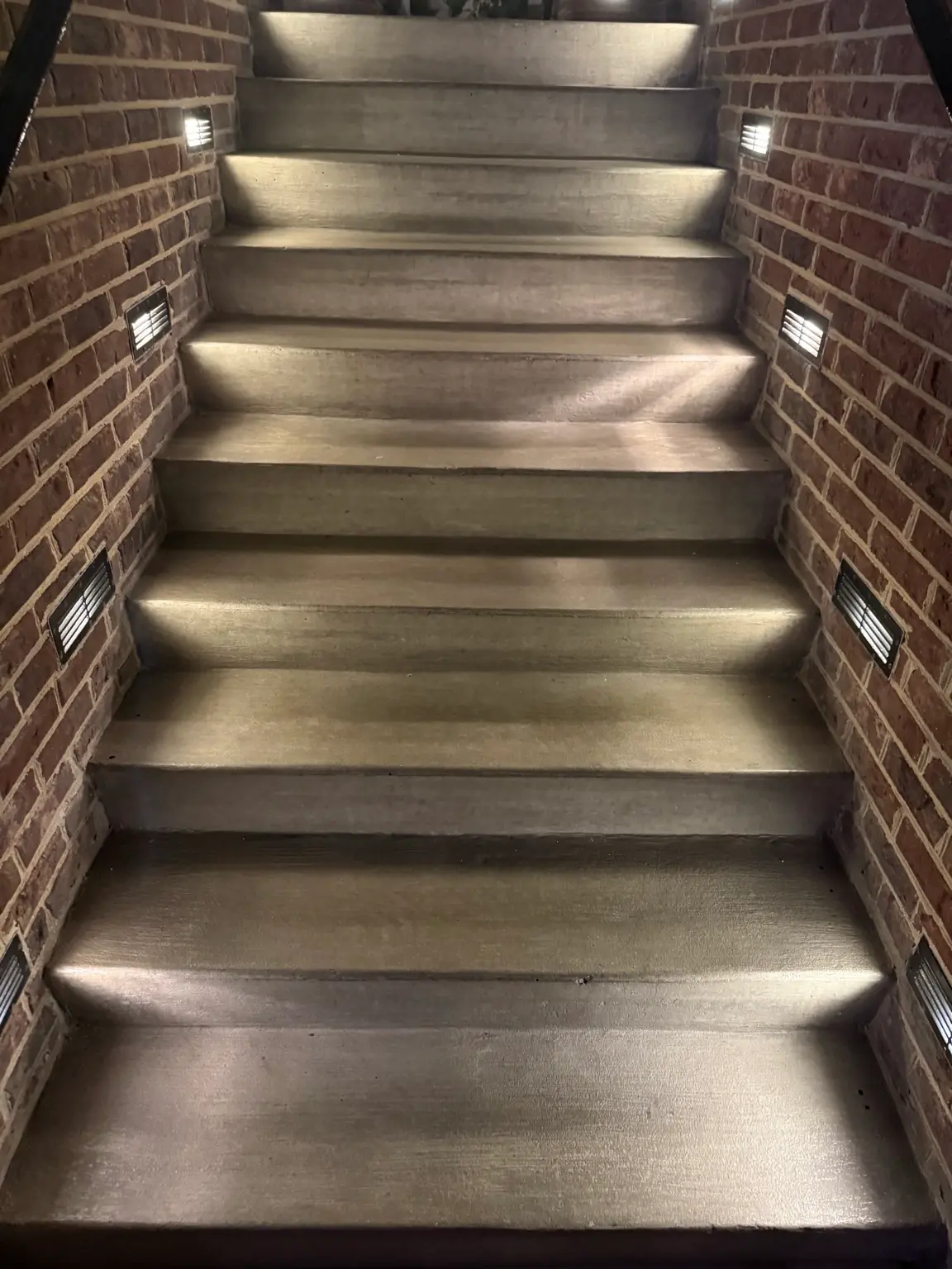 Outdoor stair step lighting mounted in brick walls showing safe low glare walkway illumination