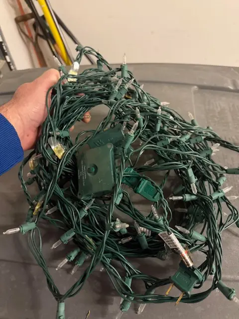 Philip Meyer troubleshooting a tangled strand of LED Christmas lights and controller box in his workshop